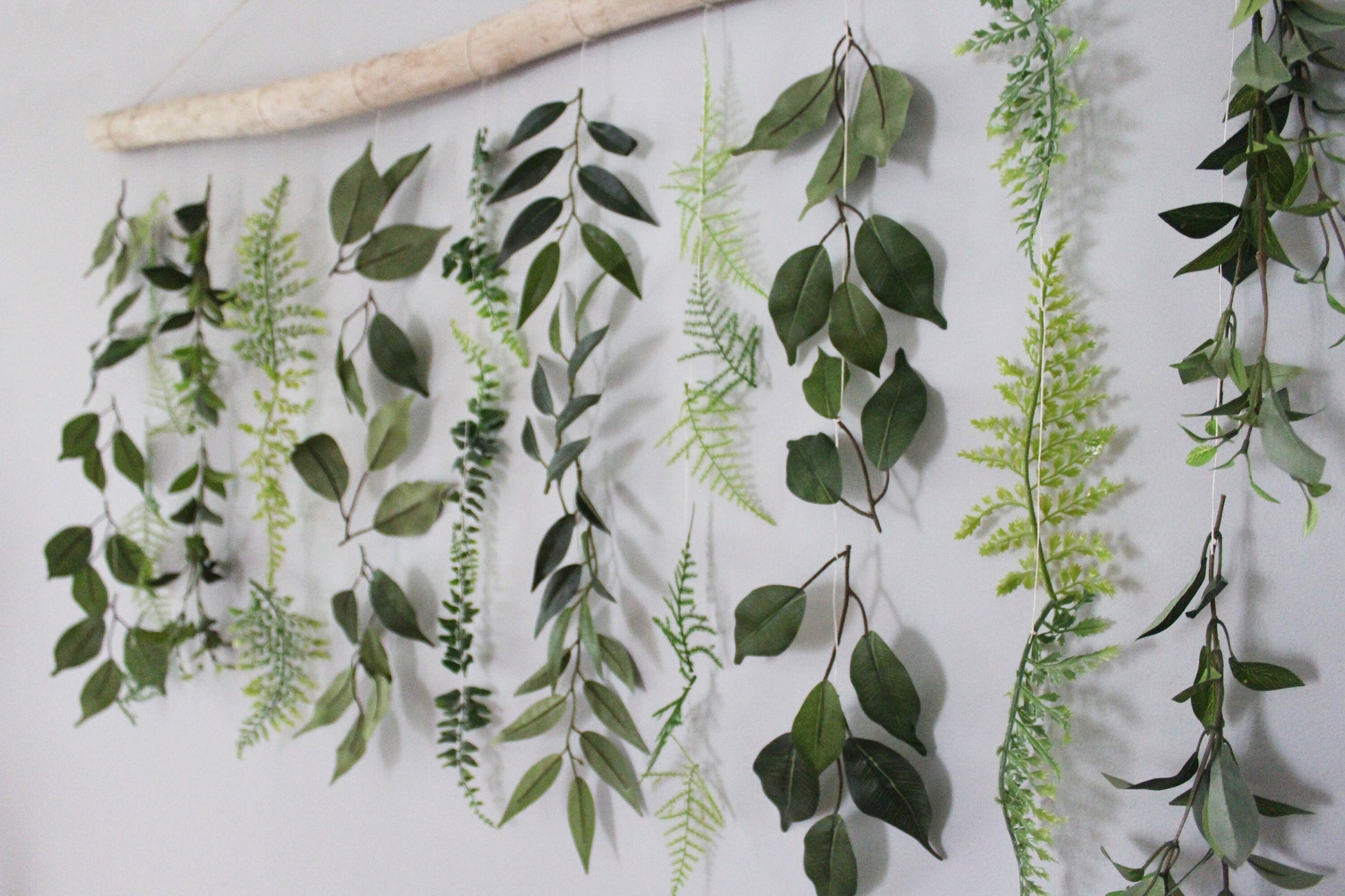 Close up of handmade wall hanging with driftwood and artificial greenery.