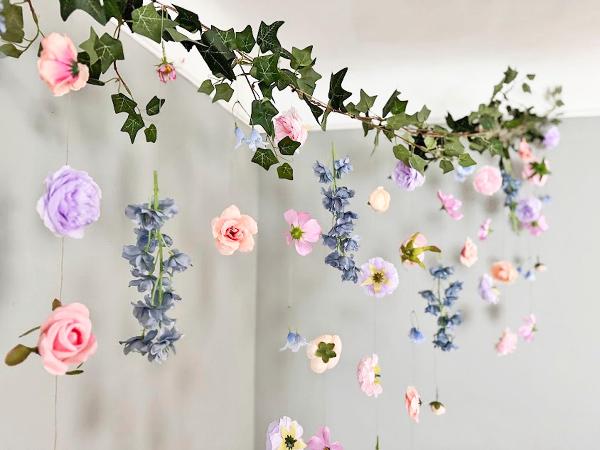 Decorative floral garland with pink, purple, and blue flowers on a plain background