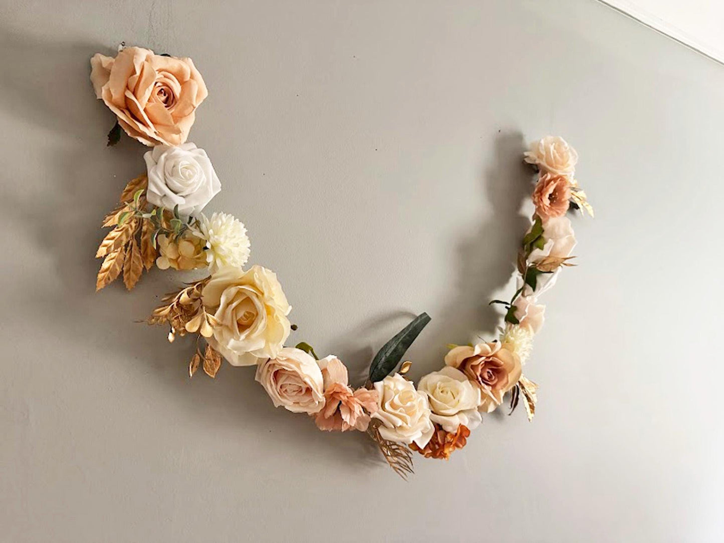 Floral garland with peach, white, and beige flowers on a light gray background