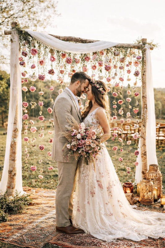 Couple embracing under a floral archway with a rustic setting