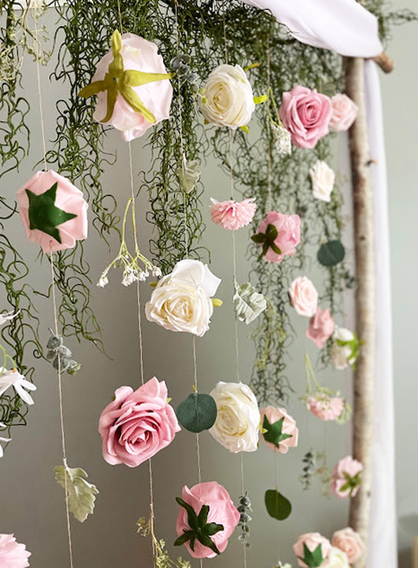 Decorative hanging floral arrangement with pink and white flowers on a neutral background
