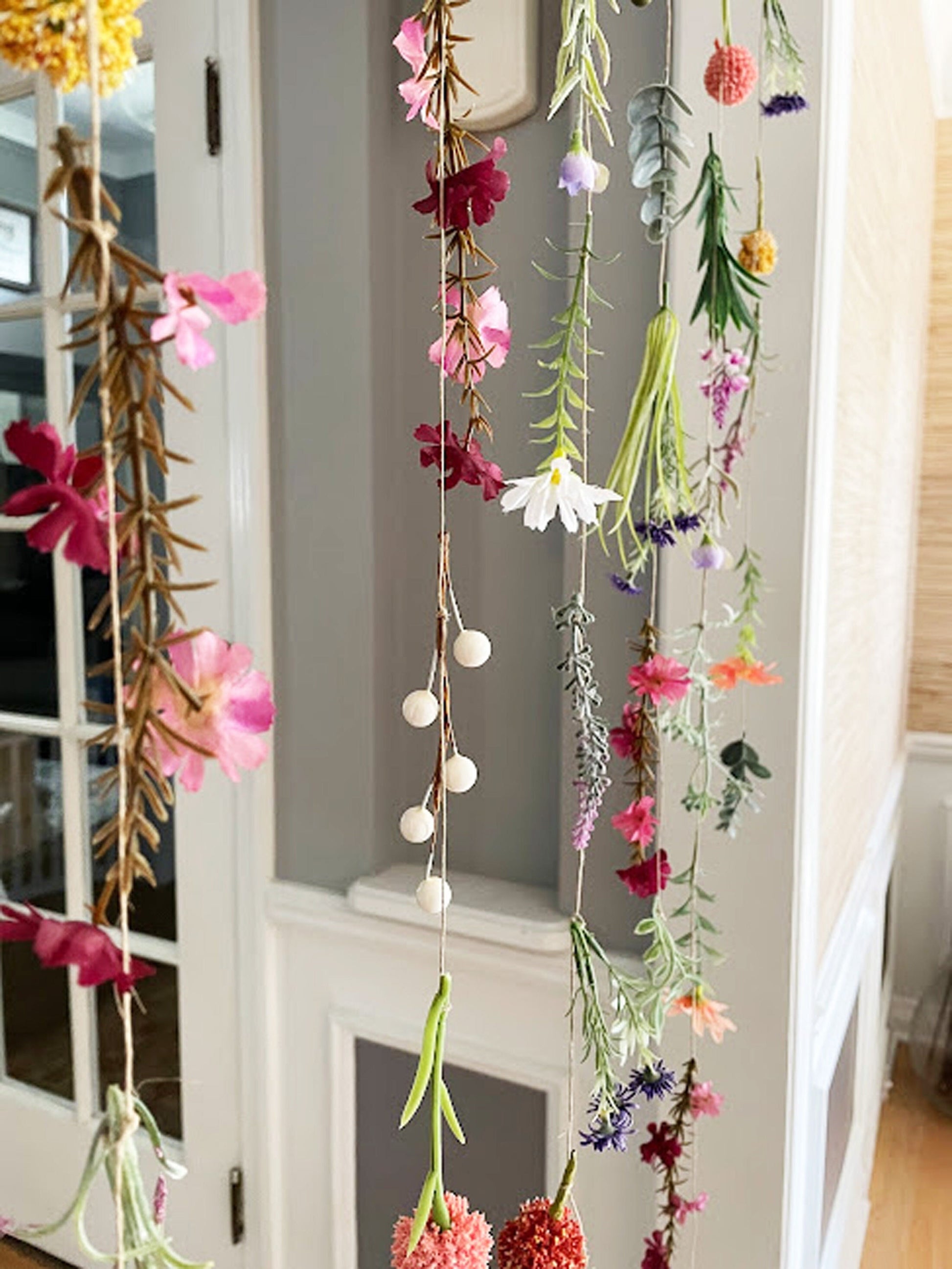 Decorative hanging floral garland with colorful flowers and greenery in a home setting.
